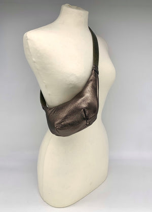 Small crossbody bag in antique gold leather worn across a mannequin