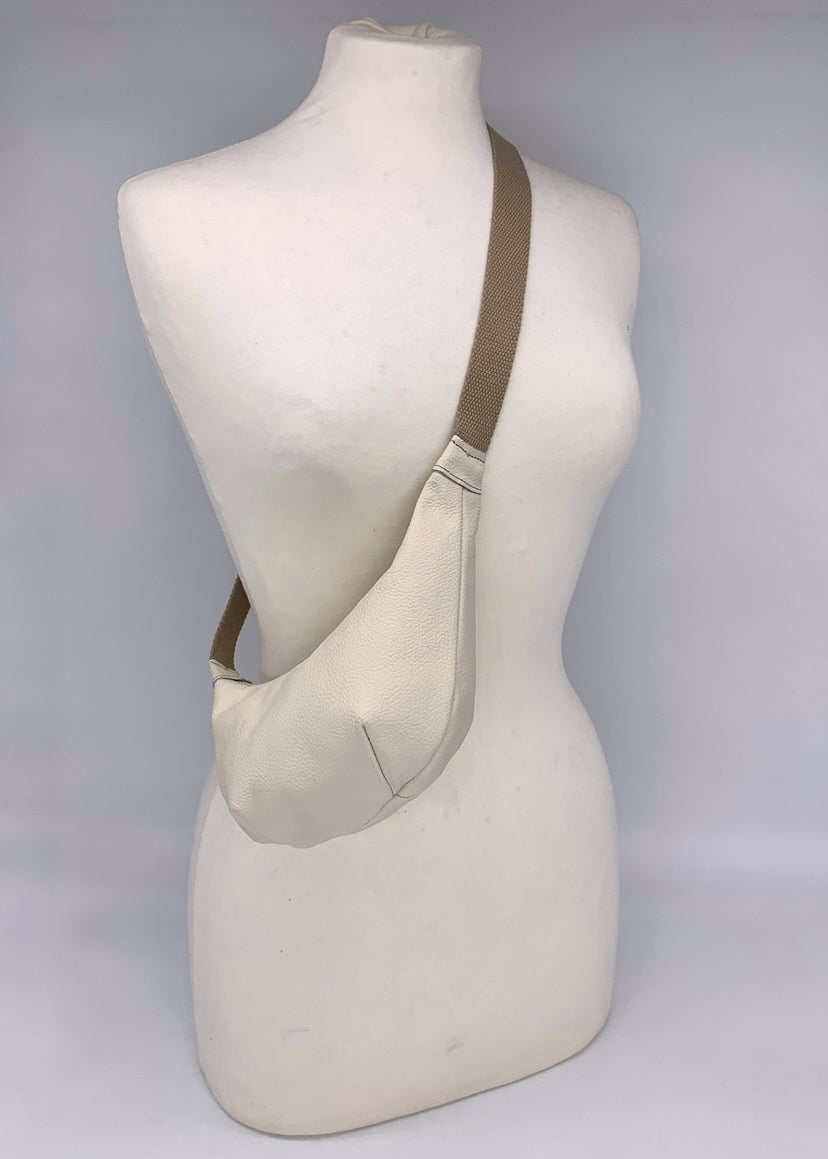 Small crossbody bag in cream leather worn across a mannequin