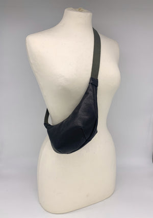 Small crossbody bag in matte black leather worn across a mannequin