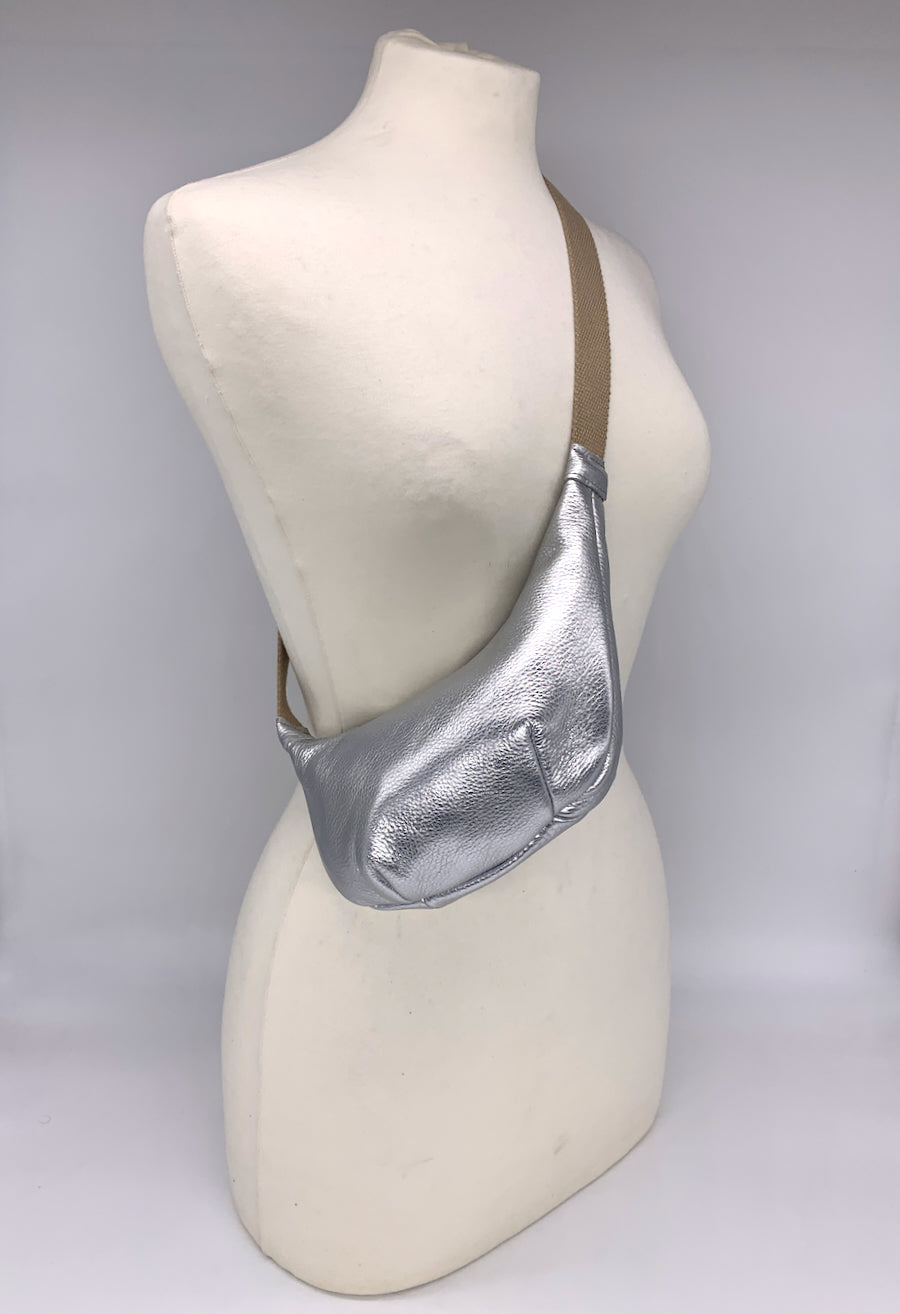 Small crossbody bag in silver leather worn across a mannequin